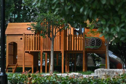 a wooden playground with a slide and a tree at Wyndham Qingdao l Free Fixed-Time Shuttle Service Between Hotel and Airport & North Railway Station l Outdoor Children's Amusement Park l 1-Hour Play Snooker or Table Tennis in Qingdao