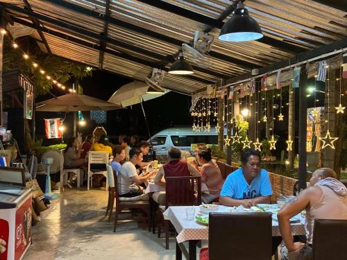 un grupo de personas sentadas en mesas en un restaurante en The Curve Residence en Ban Khao Tao