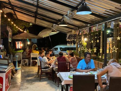 a group of people sitting at tables in a restaurant at The Curve Residence in Khao Tao