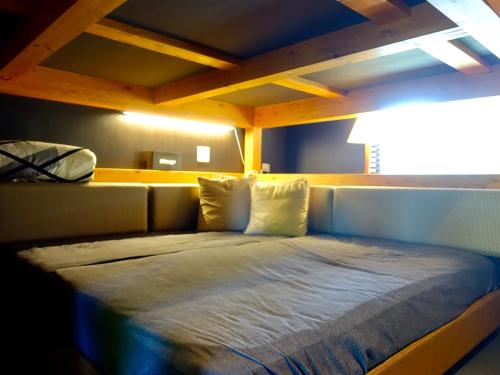 a bed in a room with a wooden ceiling at Oimatsuen in Saku