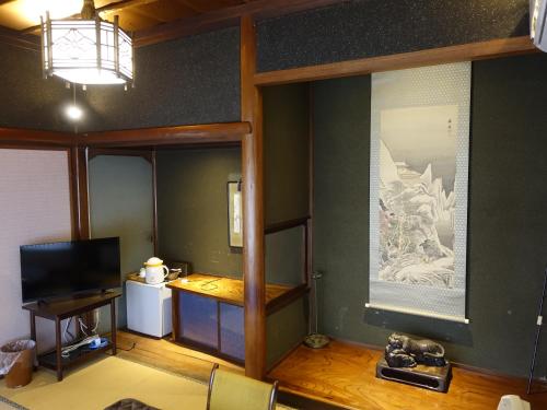 a living room with a television and a room with a table at Oimatsuen in Saku