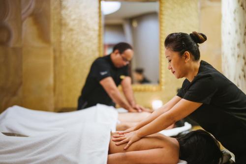 a woman sitting on a bed getting a massage at Sofitel Mumbai BKC in Mumbai