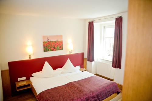 Schlafzimmer mit einem Bett mit rotem Kopfteil in der Unterkunft Gasthaus Löwen in Tuttlingen