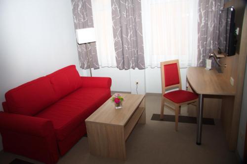 a living room with a red couch and a table at Stichwehs Hotel am Bahnhof in Elze