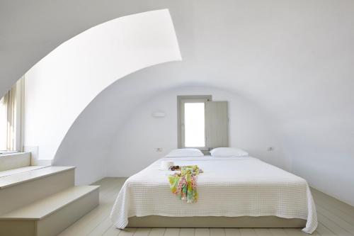 a white bed sitting in a room next to a window at Aperanto Suites in Oia