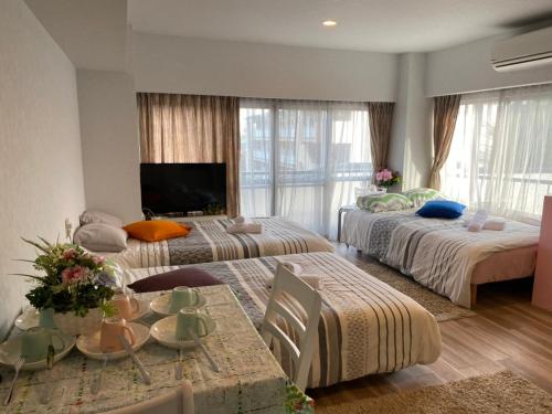 a bedroom with two beds and a table with a television at Takemura Building 303 in Tokyo