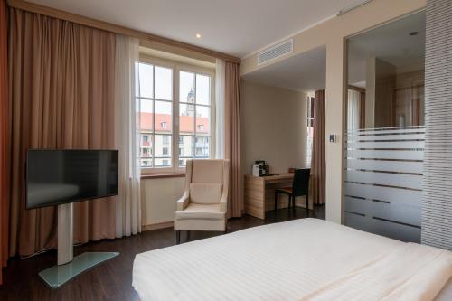 
a room with a bed, chair and a window at Star G Hotel Premium Dresden in Dresden
