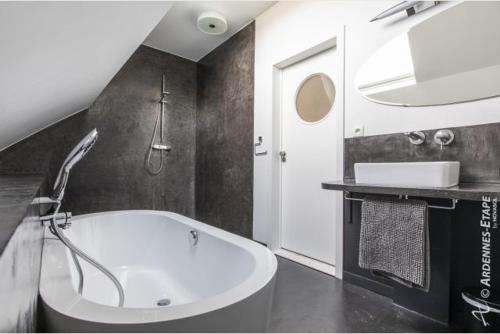 a bathroom with a white tub and a sink at Gites de la Costerie in Borsu