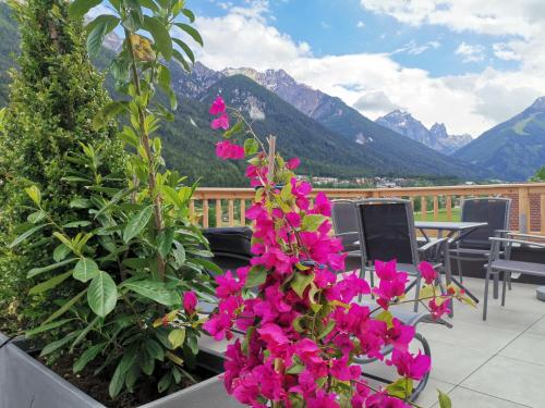 a balcony with pink flowers and a view of mountains at Ferienlandhaus Höfer in Fulpmes