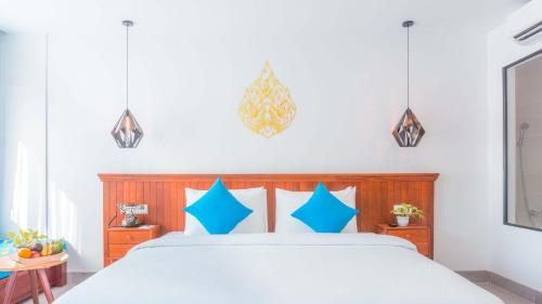 a bedroom with a large bed with blue pillows at Angkor Aurora in Siem Reap