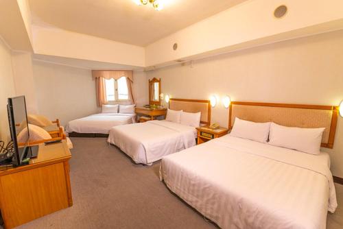 a hotel room with two beds and a flat screen tv at Kenting City Gate Hotel in Hengchun