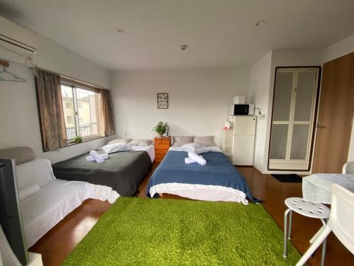 2 camas en una habitación con alfombra verde en Takemura Building 305, en Tokio