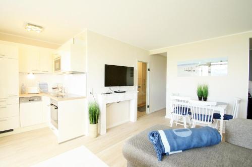 eine Küche und ein Wohnzimmer mit weißen Schränken und einem Tisch in der Unterkunft Ferienpark G11-012 Ferienpark in Heiligenhafen