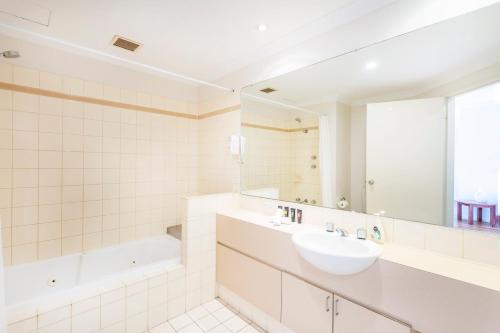 W łazience znajduje się umywalka, wanna i lustro. w obiekcie Perth West End Apartment 406 w mieście Perth