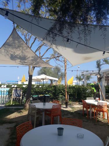 a group of tables and chairs under a white umbrella at Hotel Residenza Giardino in Bellaria-Igea Marina