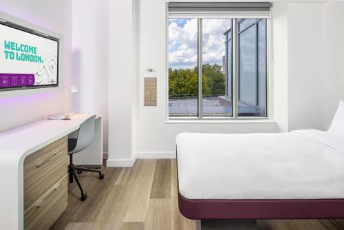 a bedroom with a bed and a desk and a window at YOTEL London City in London