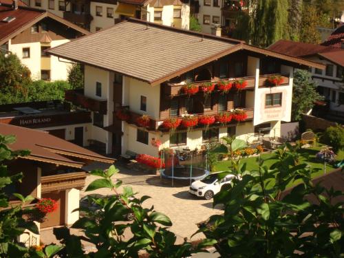 a building with flowers on the balconies in a city at Gästehaus Roland in Kirchberg in Tirol