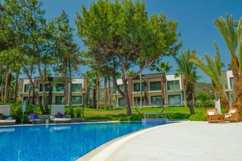 an exterior view of a resort with a swimming pool and palm trees at Hillstone Bodrum Hotel & Spa in Bodrum City