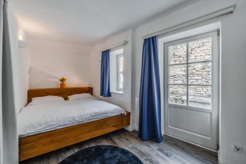 a bedroom with a bed with blue curtains and a window at Smile Apartments zum Goldenen Strauß in Dürnstein