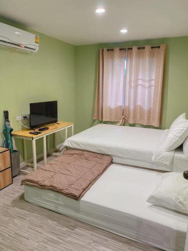 a bedroom with two beds and a desk with a television at Terrua Main Ten Villa Garden in Suan Phung