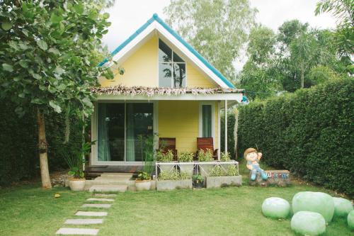 a yellow house with a teddy bear sitting in front of it at Terrua Main Ten Villa Garden in Suan Phung