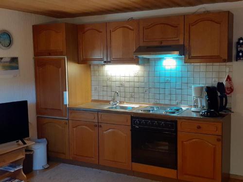 a kitchen with wooden cabinets and a stove top oven at Pension & Fewos Fuchs in Mauth
