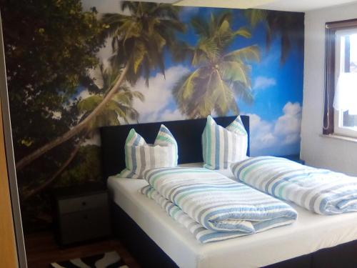 ein Bett mit Kissen und ein Wandbild von Palmen in der Unterkunft Ferienwohnung in Harzungen