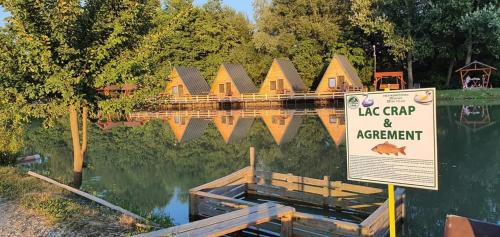 a lake camp and apartment sign in front of a lake with a lake cleanup sign at Pastravaria Zavoi in Valea Danului