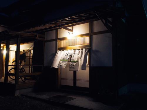 a building with a sign on the door at night at Kinoya Hostel in Fuji