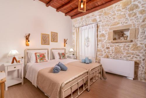 a bedroom with two beds and a stone wall at Joakim's Villa in Pitsidia