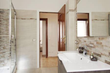 bagno con lavandino, doccia e specchio di Al Portico d'Ottavia a Roma