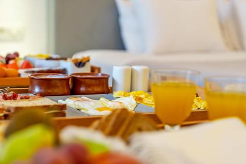 a table topped with plates of food and glasses of orange juice at Central Fira Suites in Fira
