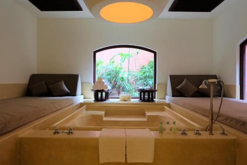 ein Bad mit einer Badewanne, einem Bett und einem Fenster in der Unterkunft Hyatt Regency Hua Hin in Hua Hin