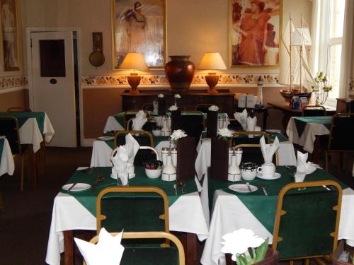 a dining room with tables with green and white tablecloths at Somerton Lodge in Shanklin