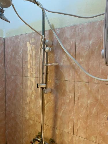 prysznic z wężem przymocowanym do ściany wyłożonej kafelkami w obiekcie Mondi Lodge Kisoro w mieście Kisoro
