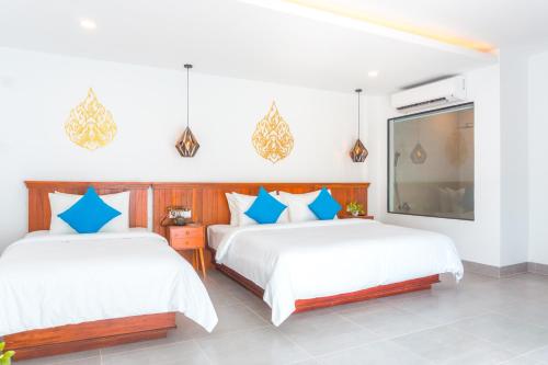 two beds in a room with white walls and blue pillows at Angkor Aurora in Siem Reap