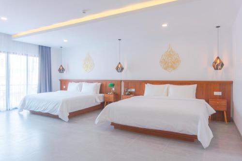 a bedroom with two beds with white sheets at Angkor Aurora in Siem Reap