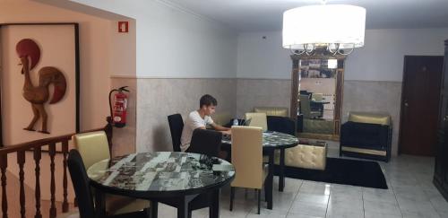Ein Mann, der an einem Tisch in einem Restaurant sitzt. in der Unterkunft Residencial Solar da Estação in Barcelos