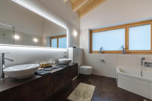 La salle de bains est pourvue de 2 lavabos, d'une baignoire et de toilettes. dans l'établissement Joe's Place - luxury lifestyle apartment, à Zermatt