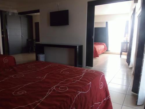 a bedroom with a red bed and a tv on the wall at Hotel Raldos Inn in Salamanca