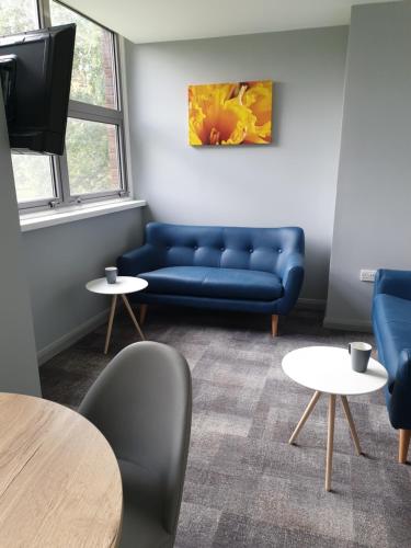 a living room with a blue couch and tables at The Spires Serviced Apartments Cardiff in Cardiff