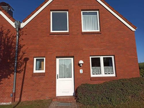a red brick house with a white door at Ferienhaus Friesenrose 45237 in Ditzum