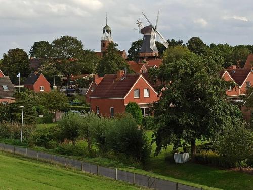 a village with houses and a windmill in the background at Ferienhaus Friesenrose 45237 in Ditzum