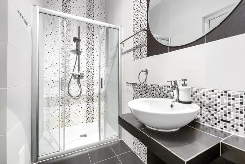a white bathroom with a sink and a shower at Apartament Leśny in Wisełka