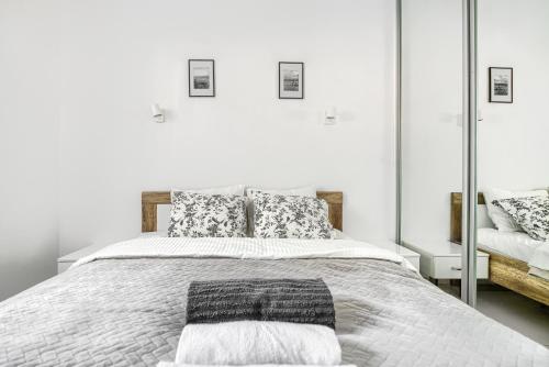 a white bedroom with a large bed and a mirror at Apartament Leśny in Wisełka