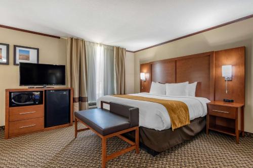 a hotel room with a bed and a flat screen tv at Comfort Suites Manhattan in Manhattan