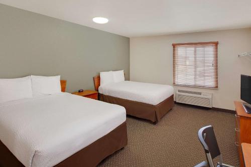 ein Hotelzimmer mit 2 Betten und einem TV in der Unterkunft WoodSpring Suites Houston I-10 West in Katy