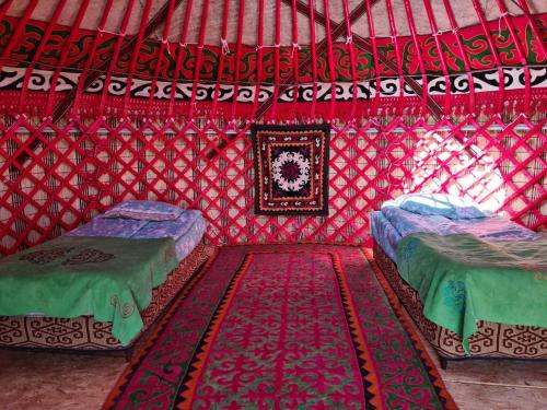 a room with two beds in a red yurt at Feel Nomad Yurt Camp in Ak-Say