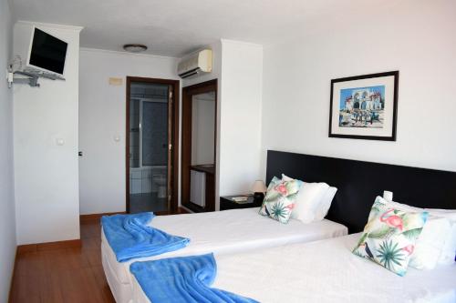 a hotel room with two beds and a television at Residência Machado in Horta