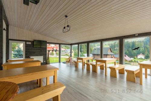 イステブナにあるApartamenty w Istebnejのテーブル、ベンチ、窓が備わる広い客室です。